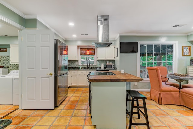 9040 Ashmere Dr, Germantown, TN 38139 - kitchen featuring washing machine and clothes dryer, appliances with stainless steel finishes, wooden counters, island exhaust hood, and white cabinetry