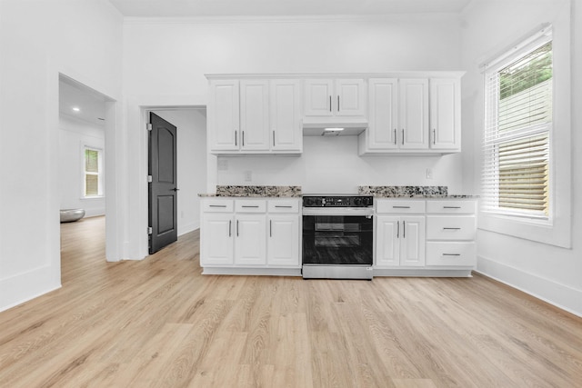 1721 Nelson Ave, Memphis, TN 38114 - kitchen featuring black electric range, white cabinetry, light wood-style floors, under cabinet range hood, and light stone counters