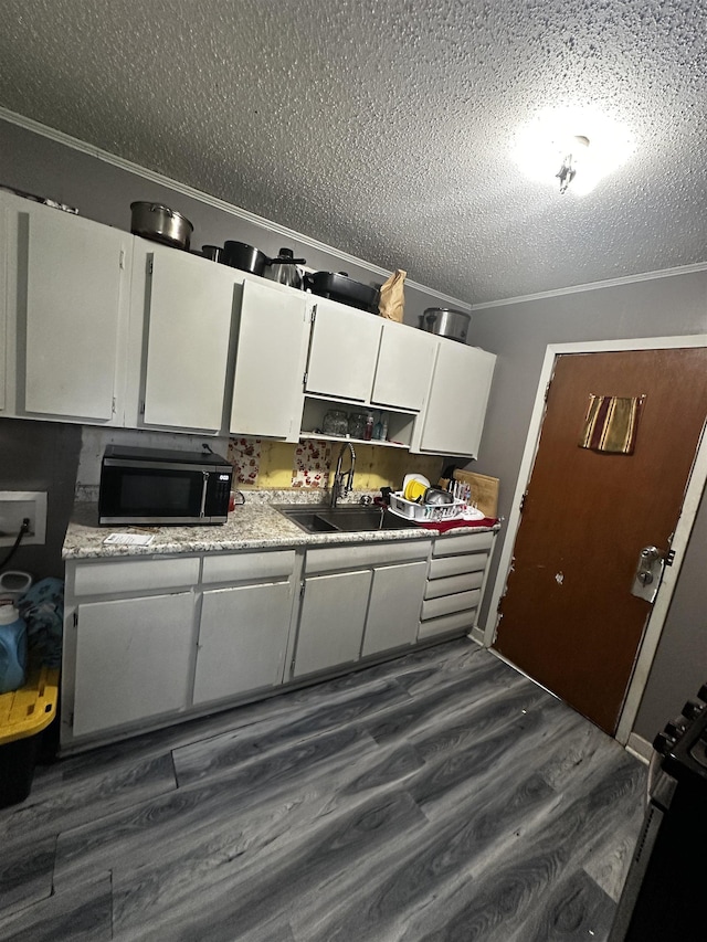 179 Appleton Ave, Memphis, TN 38109 - kitchen featuring stainless steel microwave, a textured ceiling, a sink, white cabinets, and ornamental molding