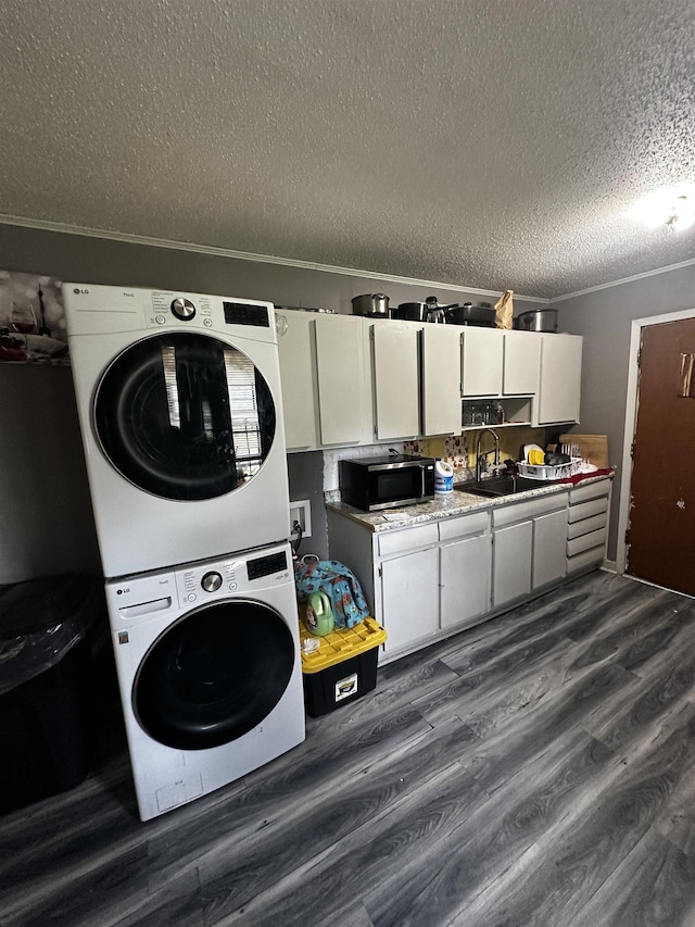 179 Appleton Ave, Memphis, TN 38109 - laundry area featuring stacked washer / dryer, a textured ceiling, dark wood-style flooring, and ornamental molding