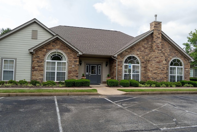 301 Stonevillage Dr W Unit 51, Collierville, TN 38017 - view of front facade featuring uncovered parking, stone siding, roof with shingles, and a chimney