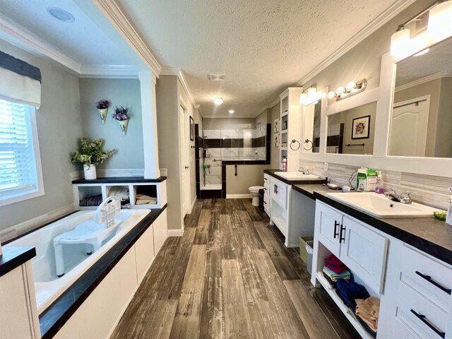 2045 Hardin Graveyard Rd, Adamsville, TN 38310 - bathroom featuring two vanities, toilet, a stall shower, wood finished floors, and a garden tub