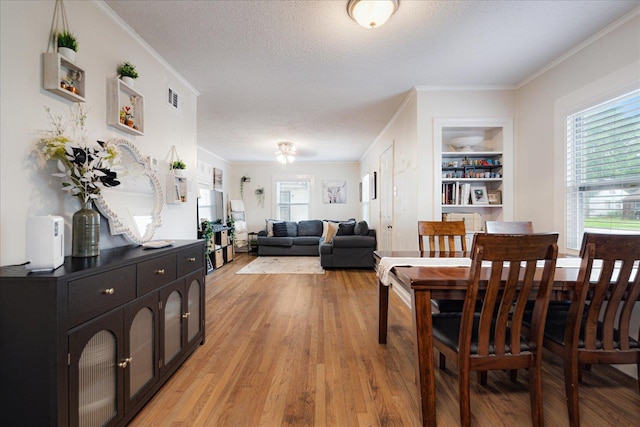 1159 Echles St, Memphis, TN 38111 - dining space featuring light wood finished floors, ornamental molding, built in shelves, and a textured ceiling