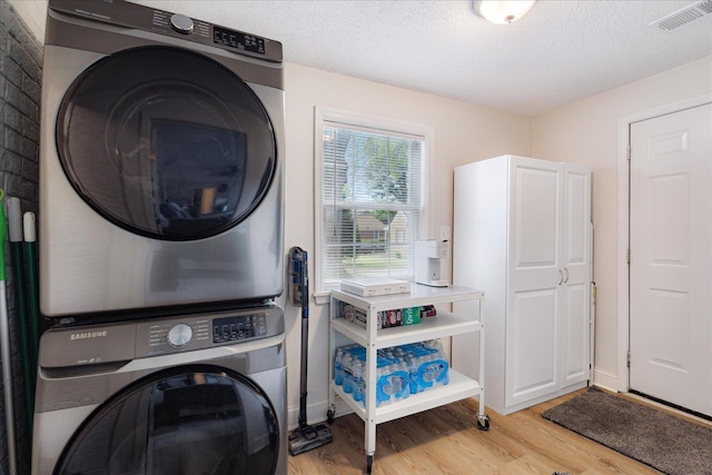 1159 Echles St, Memphis, TN 38111 - laundry area with stacked washing machine and dryer, wood finished floors, and a textured ceiling