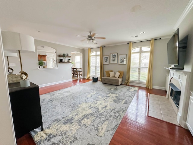 1400 Stable Run Dr, Cordova, TN 38016 - living room featuring arched walkways, a ceiling fan, a fireplace with flush hearth, wood finished floors, and crown molding