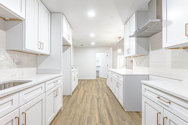 4056 Clovis Cv, Memphis, TN 38125 - kitchen featuring wall chimney exhaust hood, light wood-style floors, tasteful backsplash, white cabinetry, and recessed lighting