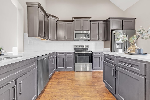 7415 Lost Grove Ln, Cordova, TN 38016 - kitchen with appliances with stainless steel finishes, tasteful backsplash, light countertops, lofted ceiling, and light wood-type flooring