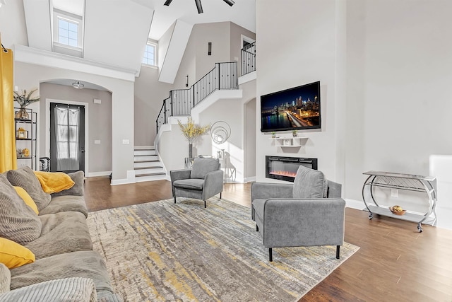 7415 Lost Grove Ln, Cordova, TN 38016 - living room featuring arched walkways, wood finished floors, a high ceiling, stairway, and a glass covered fireplace