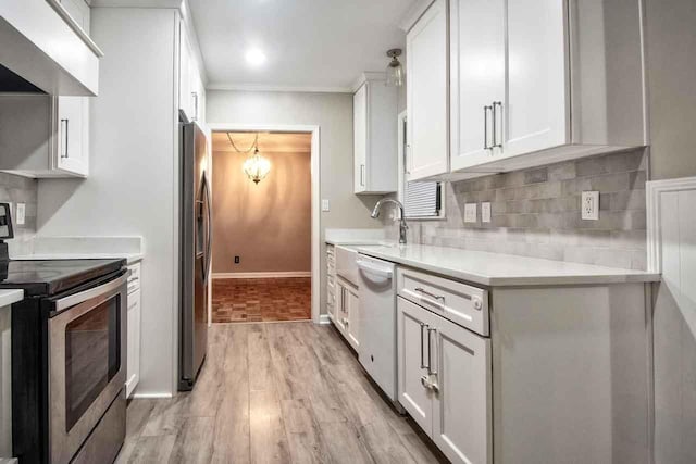 4737 Sequoia Ave, Memphis, TN 38117 - kitchen featuring appliances with stainless steel finishes, light countertops, white cabinetry, light wood-style floors, and wall chimney range hood