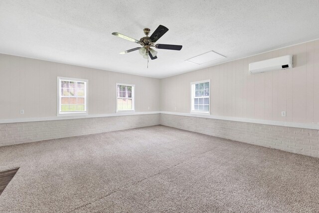3051 Overbrook Dr, Memphis, TN 38128 - carpeted empty room featuring an AC wall unit, plenty of natural light, a ceiling fan, a textured ceiling, and brick wall