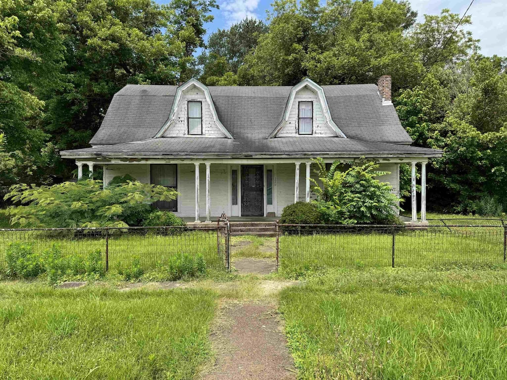 125 Memphis St, Moscow, TN 38057 - view of front facade with covered porch, a gambrel roof, a fenced front yard, a chimney, and view of scattered trees