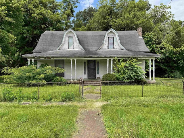 125 Memphis St, Moscow, TN 38057 - view of front facade with covered porch, a gambrel roof, a fenced front yard, a chimney, and view of scattered trees
