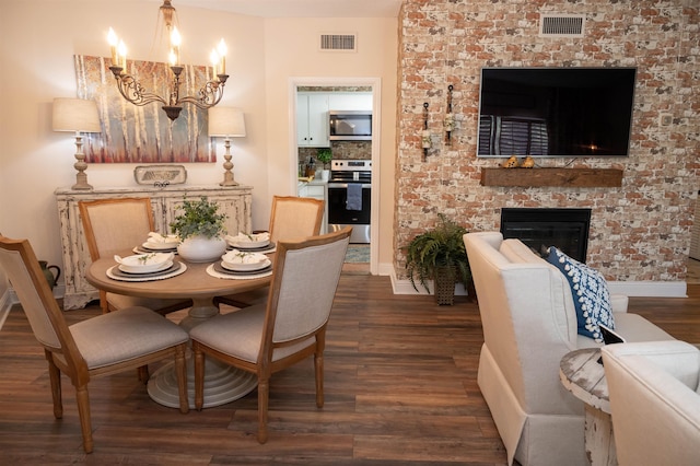475 N Highland St Unit 3H, Memphis, TN 38122 - dining area featuring dark wood-style flooring, a brick fireplace, and a chandelier