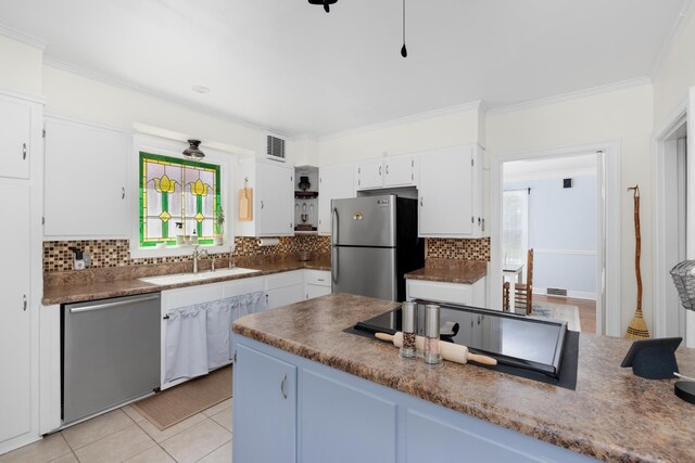 1856 N Rainbow Dr, Memphis, TN 38107 - kitchen featuring appliances with stainless steel finishes, decorative backsplash, white cabinets, light tile patterned floors, and crown molding