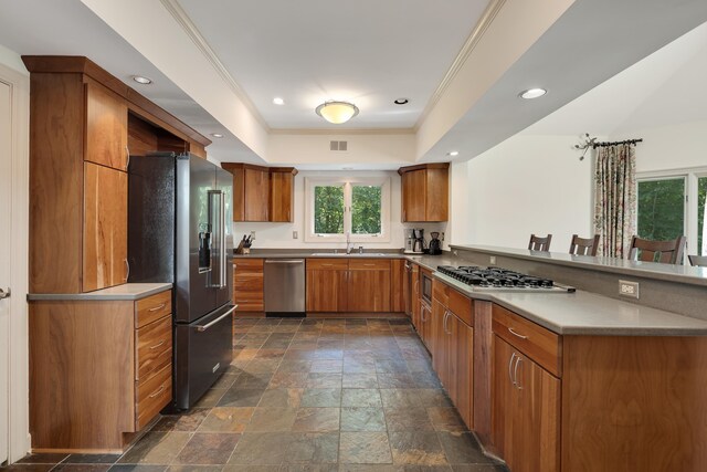 236 Riveredge Cv, Memphis, TN 38018 - kitchen featuring appliances with stainless steel finishes, a peninsula, brown cabinetry, stone tile floors, and a tray ceiling