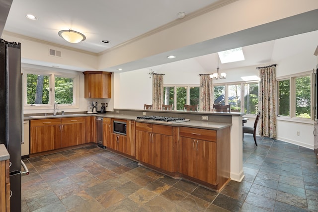 236 Riveredge Cv, Memphis, TN 38018 - kitchen featuring stone tile floors, stainless steel appliances, a peninsula, brown cabinetry, and ornamental molding