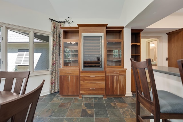 236 Riveredge Cv, Memphis, TN 38018 - kitchen with brown cabinetry, dark stone finish floors, and vaulted ceiling