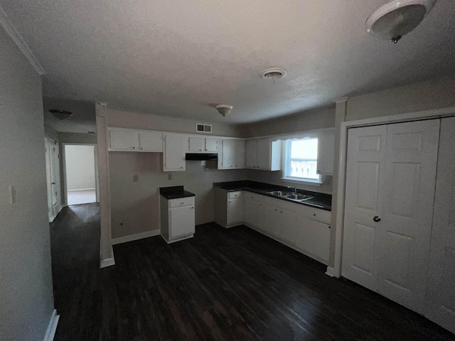 4786 Chevron Rd, Memphis, TN 38118 - kitchen featuring dark wood-type flooring, white cabinetry, under cabinet range hood, dark countertops, and a textured ceiling