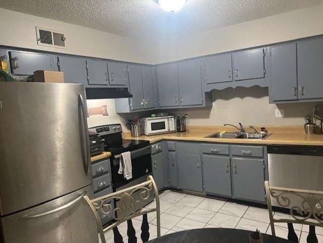 3115 S Wesley Ct, Memphis, TN 38119 - kitchen featuring stainless steel appliances, under cabinet range hood, a textured ceiling, light countertops, and gray cabinetry