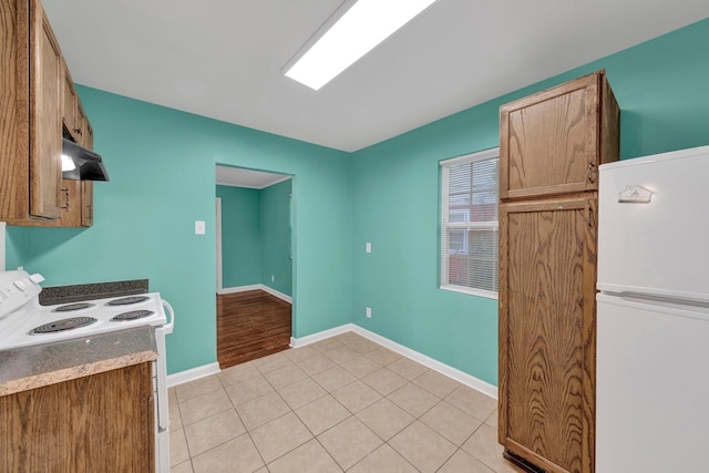 2154 N Hubert Cir, Memphis, TN 38108 - kitchen featuring white appliances, under cabinet range hood, brown cabinets, and light tile patterned floors