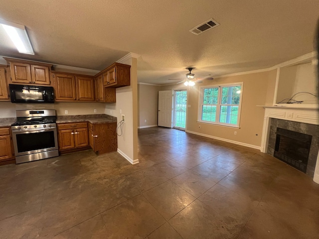 199 Bucksnort Rd, Covington, TN 38019 - kitchen with black microwave, gas range, ornamental molding, brown cabinetry, and ceiling fan