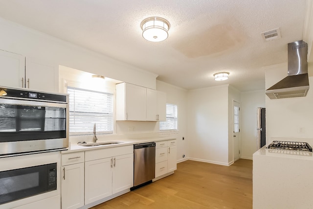 4143 Hilldale Ave, Memphis, TN 38117 - kitchen with stainless steel appliances, wall chimney range hood, light countertops, white cabinets, and a textured ceiling