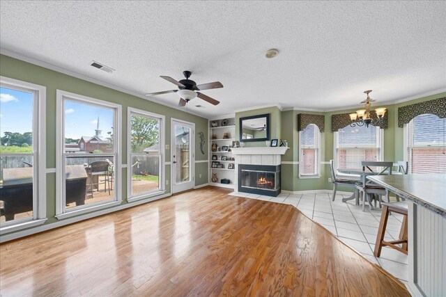 6806 Briarfield Ln, Bartlett, TN 38135 - living room featuring ornamental molding, a chandelier, a textured ceiling, a tile fireplace, and wood finished floors
