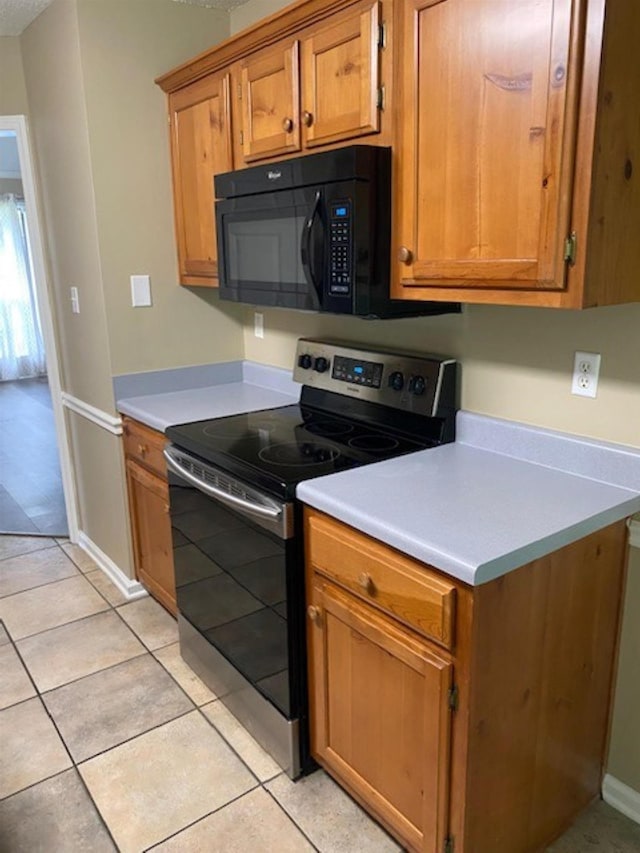 4769 Shadow View Ln, Bartlett, TN 38002 - kitchen with stainless steel electric range, black microwave, light countertops, brown cabinetry, and light tile patterned flooring