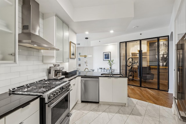 717 Riverside Dr Unit 1403, Memphis, TN 38103 - kitchen with appliances with stainless steel finishes, wall chimney exhaust hood, dark countertops, a peninsula, and white cabinets