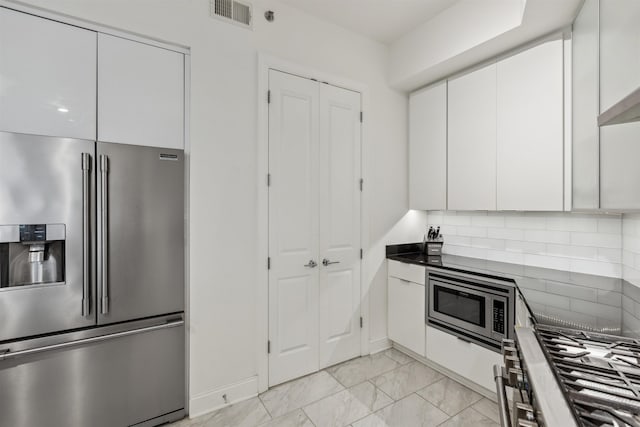 717 Riverside Dr Unit 1403, Memphis, TN 38103 - kitchen featuring stainless steel appliances, white cabinets, light marble finish flooring, tasteful backsplash, and dark countertops