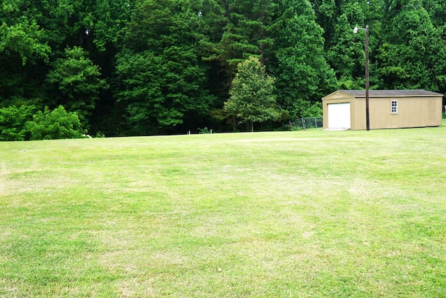 227 Lake Shore Dr, Munford, TN 38058 - view of grassy yard featuring a shed, a garage, and a forest view