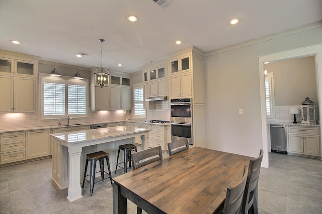 3181 Chapel Woods Cv, Germantown, TN 38139 - kitchen featuring appliances with stainless steel finishes, tasteful backsplash, a center island, a kitchen breakfast bar, and under cabinet range hood