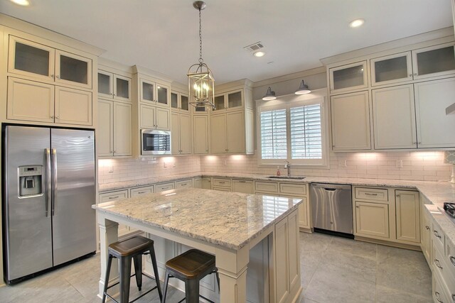 3181 Chapel Woods Cv, Germantown, TN 38139 - kitchen featuring stainless steel appliances, tasteful backsplash, a kitchen island, light stone countertops, and hanging light fixtures