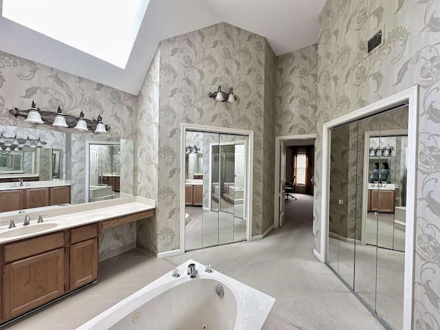 9168 Sycamore Creek Cv, Germantown, TN 38139 - bathroom with vaulted ceiling, a whirlpool tub, vanity, a skylight, and wallpapered walls