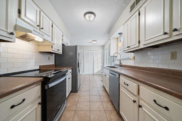 1425 Treehaven Cv, Memphis, TN 38016 - kitchen featuring stainless steel appliances, under cabinet range hood, dark countertops, backsplash, and a textured ceiling