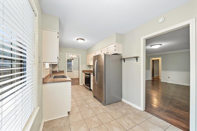 1425 Treehaven Cv, Memphis, TN 38016 - kitchen featuring stainless steel fridge, a textured ceiling, light tile patterned flooring, white cabinets, and a chandelier