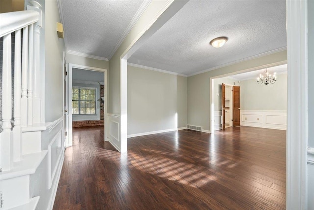 1425 Treehaven Cv, Memphis, TN 38016 - empty room with a chandelier, dark wood-style flooring, a textured ceiling, a decorative wall, and wainscoting