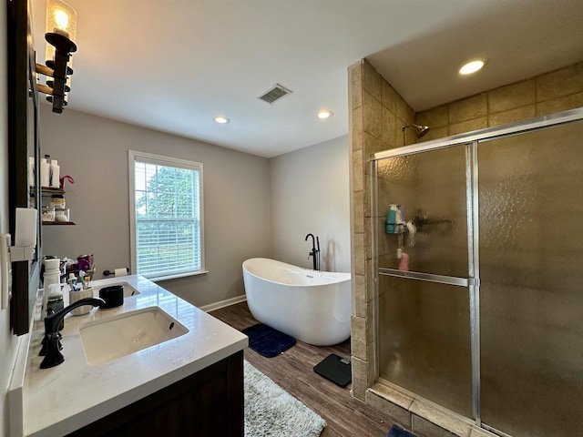 520 Jernigan Dr, Somerville, TN 38068 - full bathroom with a stall shower, wood finished floors, a freestanding tub, double vanity, and recessed lighting