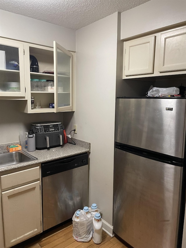 109 N Main St Unit 1202, Memphis, TN 38103 - kitchen featuring appliances with stainless steel finishes, light wood finished floors, light countertops, glass insert cabinets, and a textured ceiling