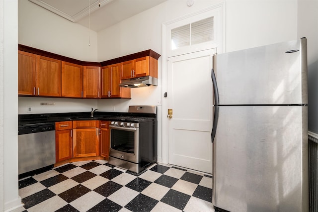 378 Mulberry St, Memphis, TN 38103 - kitchen with stainless steel appliances, under cabinet range hood, light floors, dark countertops, and brown cabinetry