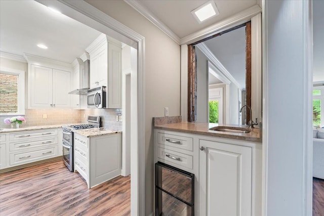 4654 Hemlock Ln, Memphis, TN 38117 - kitchen featuring appliances with stainless steel finishes, crown molding, tasteful backsplash, white cabinetry, and light wood-type flooring