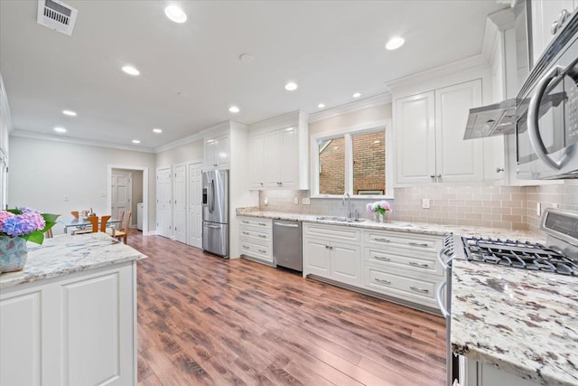 4654 Hemlock Ln, Memphis, TN 38117 - kitchen featuring appliances with stainless steel finishes, crown molding, white cabinetry, tasteful backsplash, and wood finished floors