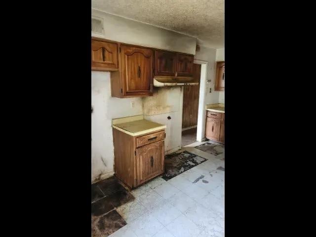 3394 Point Pleasant Ave, Memphis, TN 38118 - kitchen with light countertops, a textured ceiling, and brown cabinetry