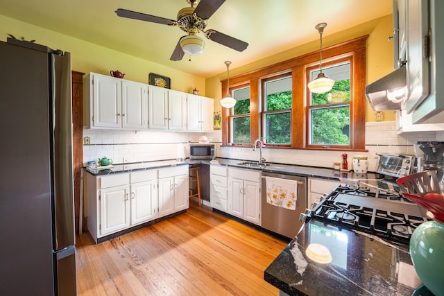 1668 Forest Ave, Memphis, TN 38112 - kitchen featuring stainless steel appliances, white cabinetry, decorative light fixtures, and tasteful backsplash