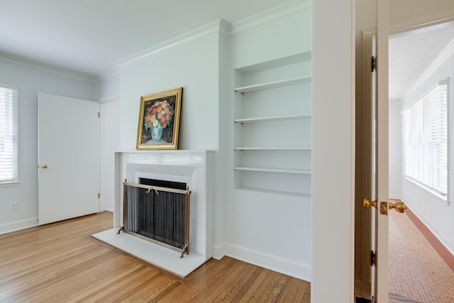5208 Gwynne Rd, Memphis, TN 38117 - unfurnished living room featuring a fireplace, built in features, ornamental molding, plenty of natural light, and wood finished floors