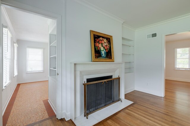 5208 Gwynne Rd, Memphis, TN 38117 - unfurnished living room with built in shelves, crown molding, wood finished floors, and a fireplace
