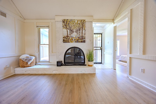 4447 Ross Rd, Memphis, TN 38141 - unfurnished living room featuring lofted ceiling, a brick fireplace, wood finished floors, and healthy amount of natural light