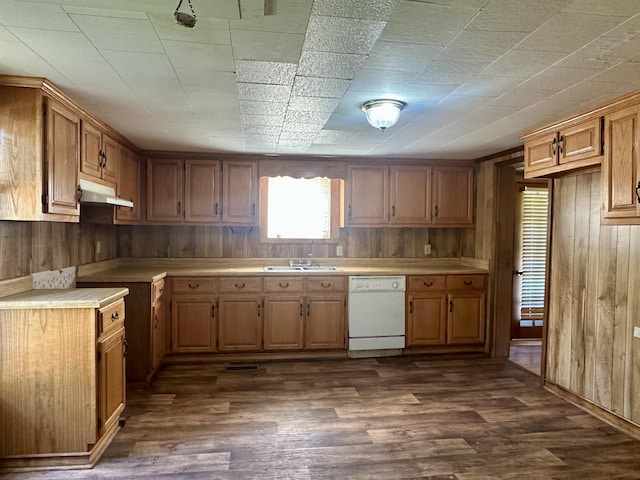 312 Pharr Ave, Selmer, TN 38375 - kitchen featuring white dishwasher, under cabinet range hood, wooden walls, light countertops, and dark wood-style floors