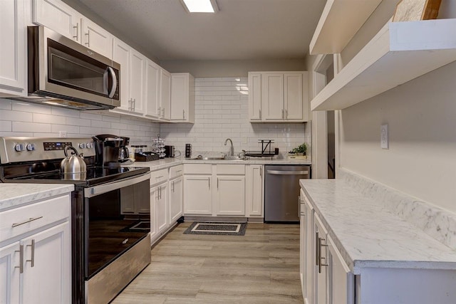1680 Euclid Ave, Memphis, TN 38114 - kitchen featuring stainless steel appliances, white cabinets, tasteful backsplash, light wood-type flooring, and light stone counters