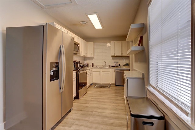 1680 Euclid Ave, Memphis, TN 38114 - kitchen featuring appliances with stainless steel finishes, tasteful backsplash, light countertops, light wood-style flooring, and white cabinetry